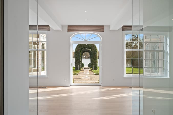 Lichte woonkamer met zicht op een perfect aangelegde tuin via een grote glazen deur, vastgelegd voor vastgoedpromotie.